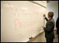 President George W. Bush signs a dry erase board with a permanent marker as he passes through a locker room during his visit to Tipp City High School in Tipp City, Ohio, Thursday, April 19, 2007. White House photo by Eric Draper