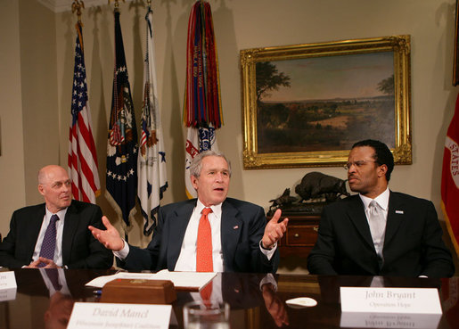 President George W. Bush gestures as he talks with reporters following a meeting on financial literacy Wednesday, April 25, 2007 in the Roosevelt Room at the White House, where President Bush said he has directed U.S. Secretary of the Treasury Henry Paulson, left, to develop and hone a strategy that will help more of our American citizens to become financially literate.John Bryant, president and CEO of Operation Hope, is seen at right. White House photo by Eric Draper