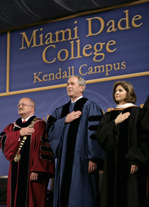 President George W. Bush stands for the national anthem onstage at Miami Dade College - Kendall Campus in Miami Saturday, April 28, 2007, before delivering the 2007 commencement address. With him are Miami Dade College President Dr. Eduardo Padron and Helen Aquirre Ferre, Chairman of the Board of Trustees at Miami Dade College. White House photo by Eric Draper