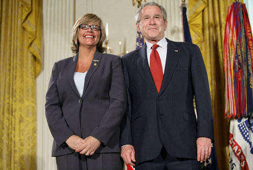 President George W. Bush joins military spouse Cindy Bjerke of Spanaway, Wash., on stage in the East Room of the White House, to receive the President’s Volunteer Service Award Friday, May 11, 2007, during a commemoration of Military Spouse Day. White House photo by Eric Draper