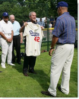 President George W. Bush holds up a commemorative baseball jersey with Jackie Robinson's number 42 presented to him by players from Robinson's playing era at the White House Tee Ball Game Sunday, July 15, 2007. Tee Ball players wore the number 42 to celebrate the legacy of Jackie Robinson. More about Tee Ball on the South Lawn. White House photo by Chris Greenberg