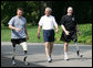 President George W. Bush meets with wounded veterans U.S. Army Sgt. Neil Duncan (Ret.), left, and U.S. Army Specialist Max Ramsey, right, for a jog Wednesday, July 25, 2007 around the South Lawn of the White House. White House photo by Eric Draper