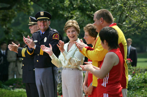 Mrs. Laura Bush and her fellow stage participates applaud runner Karen Dickerson of Springfield, Va., during a Special Olympics Global Law Enforcement Torch Run Ceremony Thursday, July 26, 2007, in the Rose Garden. "Karen is a tireless advocate for her fellow athletes. She's what we call a fierce competitor," said the President in his remarks. "In the 2003 World Games in Ireland, Karen was told that she had a stress fracture in her leg. Yet, through sheer willpower, she won the Bronze Medal." White House photo by Eric Draper