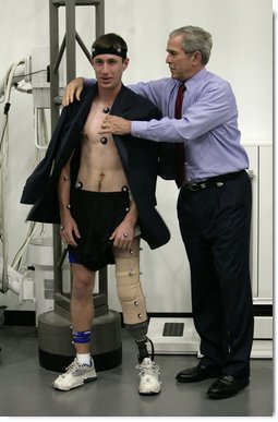 President George W. Bush offers his jacket to U.S. Army PFC Nicholas Clark of Seattle, Wash., during his visit Thursday, Nov. 8, 2007 to the Gait Lab at the Center for The Intrepid at the Brooke Army Medical Center in San Antonio, Texas. PFC Clark, who lost a leg while serving in Afghanistan in 2007, is participating in a demonstration wearing retro-reflective markers to measure his body movements under infra-red cameras. White House photo by Eric Draper