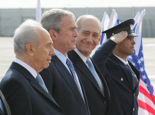 President George W. Bush elicits a smile from Israel’s Prime Minister Ehud Olmert, right, as they join Israeli President Shimon Peres for arrival ceremonies Wednesday, Jan. 9, 2008, at Ben Gurion International Airport in Tel Aviv. White House photo by Eric Draper