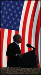 President George W. Bush stands in front of a U.S. flag Saturday, Jan. 12, 2008, as he addresses military personnel and coalition forces at Camp Arifjan in Kuwait. The President told the troops, "It's hard work you're doing, but it's necessary work." White House photo by Eric Draper