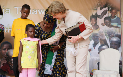 Mrs. Laura Bush pats the back of 7-year-old Zuena Dotto, after she presented Mrs. Bush with a scrapbook during the launch of the National Plan for Action event at the WAMA Foundation Sunday, Feb. 17, 2008, in Dar es Salaam. White House photo by Eric Draper