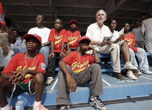 President George W. Bush sits in the stands and watches a tee ball game Wednesday, Feb. 20, 2008, at the Ghana International School in Accra, Ghana. White House photo by Eric Draper