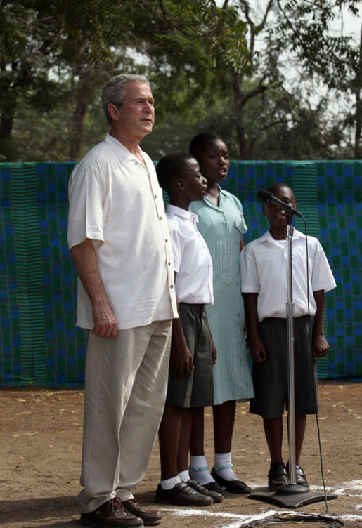 President George W. Bush stands at home plate with 3 members of the Ghana International School choir as they sing the Ghanaian National Anthem Wednesday, Feb. 20, 2008, at a tee ball game at the Ghana International School in Accra, Ghana. White House photo by Eric Draper