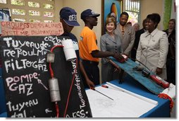 Mrs. Laura Bush, joined by Guerda Previlon, right, chief of party IDEJEN, and Gabriel Bienime, Haiti Education Minister, visits with a student enrolled in the IDEJEN educational program at the College de St. Martin Tours Thursday, March 13, 2008, in Port-au-Prince, Haiti. In an address to the faculty and staff Mrs. Bush said, “Educating its young people is one of the best things a country can do to ensure its continued development.” White House photo by Shealah Craighead