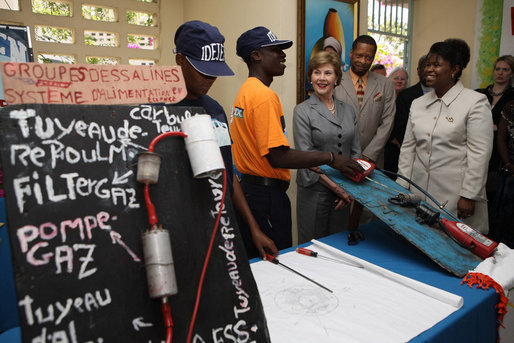 Mrs. Laura Bush, joined by Guerda Previlon, right, chief of party IDEJEN, and Gabriel Bienime, Haiti Education Minister, visits with a student enrolled in the IDEJEN educational program at the College de St. Martin Tours Thursday, March 13, 2008, in Port-au-Prince, Haiti. In an address to the faculty and staff Mrs. Bush said, “Educating its young people is one of the best things a country can do to ensure its continued development.” White House photo by Shealah Craighead