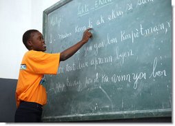 A student at the IDEJEN educational program reads from a chalkboard Thursday March, 13, 2008, during Mrs. Laura Bush's visit to the program at the College de St. Martin Tours in Port-au-Prince, Haiti. White House photo by Shealah Craighead