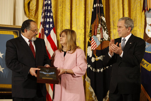 President George W. Bush leads the applause in honor of Petty Officer Michael A. Monsoor after presenting the Congressional Medal of Honor posthumously to his parents, George and Sally Monsoor, during ceremonies Tuesday, April 8, 2008, at the White House. The 25-year-old Navy SEAL was killed in Iraq in 2006 after he threw himself on a grenade to save his fellow SEALS when they came under attack while on duty in Ramadi. White House photo by Eric Draper