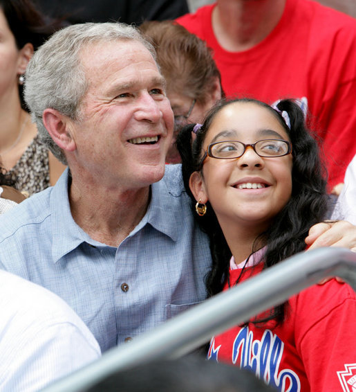 President George W. Bush poses for a photo with a fan in the stands Monday, June 30, 2008, during the opening game of the 2008 Tee Ball season between the Cramer Hill Little League Red Sox of Camden, N.J., and the Jose M. Rodriguez Little League Angels of Manati, Puerto Rico, on the South Lawn of the White House. White House photo by Chris Greenberg