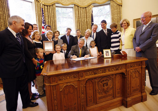 President George W. Bush signs the Caroline Pryce Walker Conquer Childhood Cancer Act of 2008 Tuesday, July 29, 2008, in the Oval Office of the White House. President Bush is joined at his desk by Mrs. Laura Bush, HHS Secretary Mike Leavitt, the Lewis family, the Adams family, the Haight family, the Rech family, and Congressional representatives Sen. Jack Reed D-RI; Minnesota Senator Norm Coleman; Rep. Deborah Pryce R-OH; and Rep. Chris Van Hollen D-MD; and CureSearch's Dr. Gregory Reaman. White House photo by Eric Draper