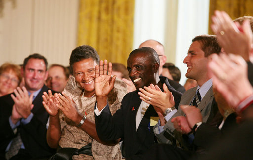 HIV/AIDS activist Mohamed Kalyesubula of Uganda waves to acknowledge the applause of guests, joined by fellow HIV/AIDS activist nurse Agnes Nyamayarwo of Uganda, left, both honored by President George W. Bush Wednesday, July 30, 2008 in the East Room of the White House, at the signing ceremony of H.R. 5501, the Tom Lantos and Henry J. Hyde United States Global Leadership Against HIV/AIDS, Tuberculosis and Malaria Reauthorization Act of 2008. White House photo by Joyce N. Boghosian