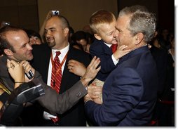 President George W. Bush is hugged by a young boy Friday, Aug. 8, 2008, during a greeting at the U.S. Embassy in Beijing.  White House photo by Eric Draper