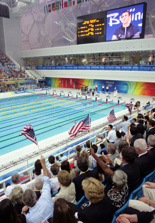 President George W. Bush waves an American flag as U.S. swimmer Michael Phelps is presented his gold medal after winning the 400-meter Individual Medley Sunday, Aug. 10, 2008, at the 2008 Summer Olympics in Beijing. White House photo by Shealah Craighead