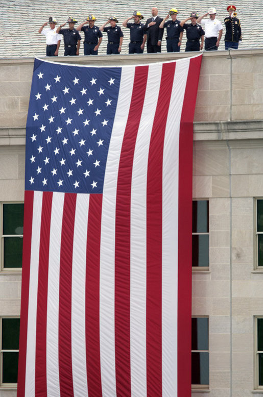 A Marine Band trumpeter plays Taps while first responders and officials salute a flag that hangs on the side of the Pentagon Thursday, Sept. 11, 2008, during the dedication of the 9/11 Pentagon Memorial at the Pentagon in Arlington, Va. White House photo by Eric Draper