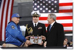 President George W. Bush is presented a piece of the flight deck of the USS Intrepid by Mike Hallahan, left, president of the United War Veterans Council of New York, also joined by military aide U.S. Navy Lt.Cmdr. Clay Beers, during the rededication ceremony Tuesday, Nov. 11, 2008, for the Intrepid Sea, Air and Space Museum in New York. White House photo by Eric Draper