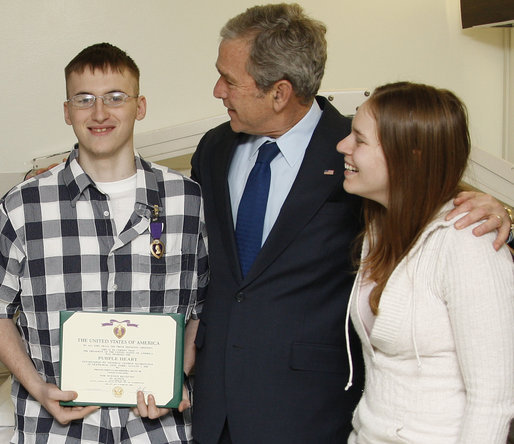 President George W. Bush congratulates U.S. Army PFC Joseph Devan of Baltimore, Md., after presenting him with a Purple Heart Monday, Dec. 22, 2008, during a visit to Walter Reed Army Medical Center, where the soldier is recovering from injuries suffered in Operation Iraqi Freedom. With them is PFC Devan's wife, Stephanie. White House photo by Eric Draper