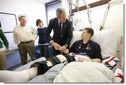 President George W. Bush shakes hands with U.S. Army Staff Sgt. Kyle Stipp of Avon, Ind., after presenting him with two Purple Hearts Monday, Dec. 22, 2008, during a visit to Walter Reed Army Medical Center where the soldier is recovering from wounds suffered in Operation Iraqi Freedom. Looking on are his wife, Megan, and father, Mitch Stipp. White House photo by Eric Draper