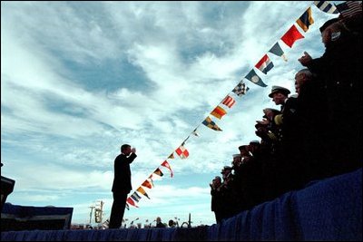 President George W. Bush salutes navy personnel aboard the USS Enterprise in Norfolk, Va., on the 60th anniversary of the Pearl Harbor attack Dec. 7, 2001. "Today we take special pride that one of our former enemies is now among America's finest friends," said the President. "We're grateful to our ally, Japan, and to its good people. Today our two Navies are working side by side in the fight against terror."