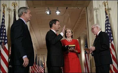 President George W. Bush watches Thursday, Sept. 29, 2005 in the East Room of the White House in Washington, as Judge John G. Roberts is sworn-in as the 17th Chief Justice of the United States by Associate Supreme Court Justice John Paul Stevens. Judge Roberts' wife Jane is seen holding the Bible.