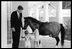 President John F. Kennedy (1961-63) spends some time at the White House with his children, Caroline and John Jr., and their pony, Macaroni. 