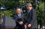 Approaching the podium, President Kwasniewski greets President Bush. "We are grateful to America, you, Mr. President, and your predecessors, for good will and help we have been receiving in Poland for dozen of years -- in all our efforts," said President Kwasniewski, addressing the crowd in English. "Poland is steadfast ally of the United States. We take over the co-responsibility for European and global security. On the 11th of September, all of us felt New Yorkers." White House photo by Susan Sterner. 