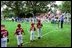 Kicking off the fourth season of White House Tee Ball, President Bush speaks during the first game of the 2004 season June 13, 2004. President Bush started the league to encourage foster a spirit of teamwork and service in America's youth.