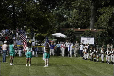 President George W. Bush stands for the singing of the national anthem with representatives of the All-American Girls Professional Baseball League Players Association during the opening ceremony for the last game of the 2003 White House South Lawn Tee Ball season Sunday, Sept. 7, 2003. The AAGPBL gave more than 600 woman the opportunity to play professional baseball from 1943 to 1954.