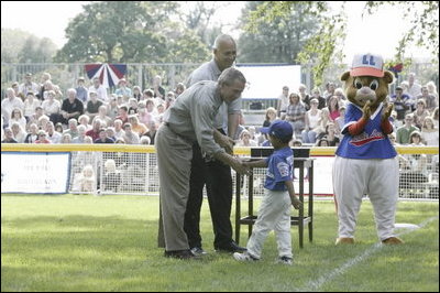 President George W. Bush and Honorary Commissioner Cal Ripken present a little leaguer with a warm congratulations and an autographed baseball after playing the last game of the 2003 White House South Lawn Tee Ball season Sunday, Sept. 7, 2003.