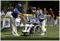 A player from the District 12 Little League Challengers from Williamsport, PA is helped to home plate by her buddy during a Tee Ball game on the South Lawn of the White House on Sunday July 24, 2005.