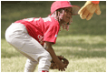 Taylor Paige Nevils of South Side Little League Memphis Red Sox from Chicago, peers up at Dugout, the Little League mascot, during a T-ball game on the South Lawn Sunday, June 26, 2005.