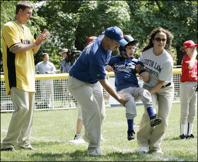 A player for the Shady Spring Little League Challenger Braves of Shady Spring W. Va., is helped around the bases Sunday, July 30, 2006, at the White House Tee Ball on the South Lawn game against the Thurmont Little League Civitan Club of Frederick Challengers of Thurmont, Md. 