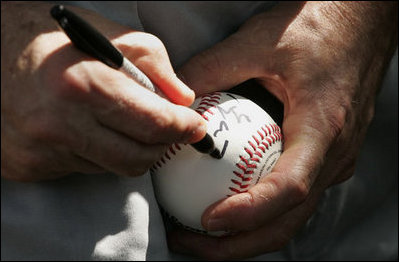 President George W. Bush autographs baseballs for players and guests at the White House Sunday, July 30, 2006, during the Tee Ball on the South Lawn game between the Thurmont Little League Civitan Club of Frederick Challengers of Thurmont, Md., and the Shady Spring Little League Challenger Braves of Shady Spring, W. Va. 