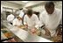 White House Executive Chef, Cristeta " Cris" Comerford, background-left in chef's hat, helps prepare trays of food, Wednesday, Nov. 2, 2005, in the White House kitchen, in preparations for the official dinner for the Prince of Wales and Duchess of Cornwall.